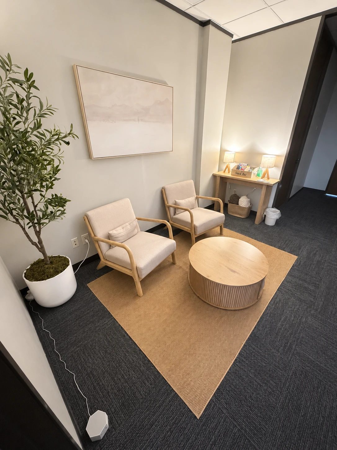 The Poplar Belief Therapy office: two cream armchairs, a round wood table and an olive tree